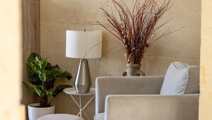 A living room with a grey sofa, a white lamp on a small table, and a potted plant. - ROOFTOP HIDEAWAY, JACUZZI, BBQ & PETss (L-Għarb)