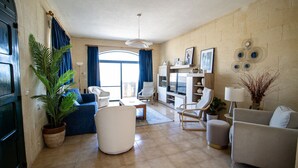 A living room with a sofa, chairs, a coffee table, a TV, and a dining area. - ROOFTOP HIDEAWAY, JACUZZI, BBQ & PETss (L-Għarb)