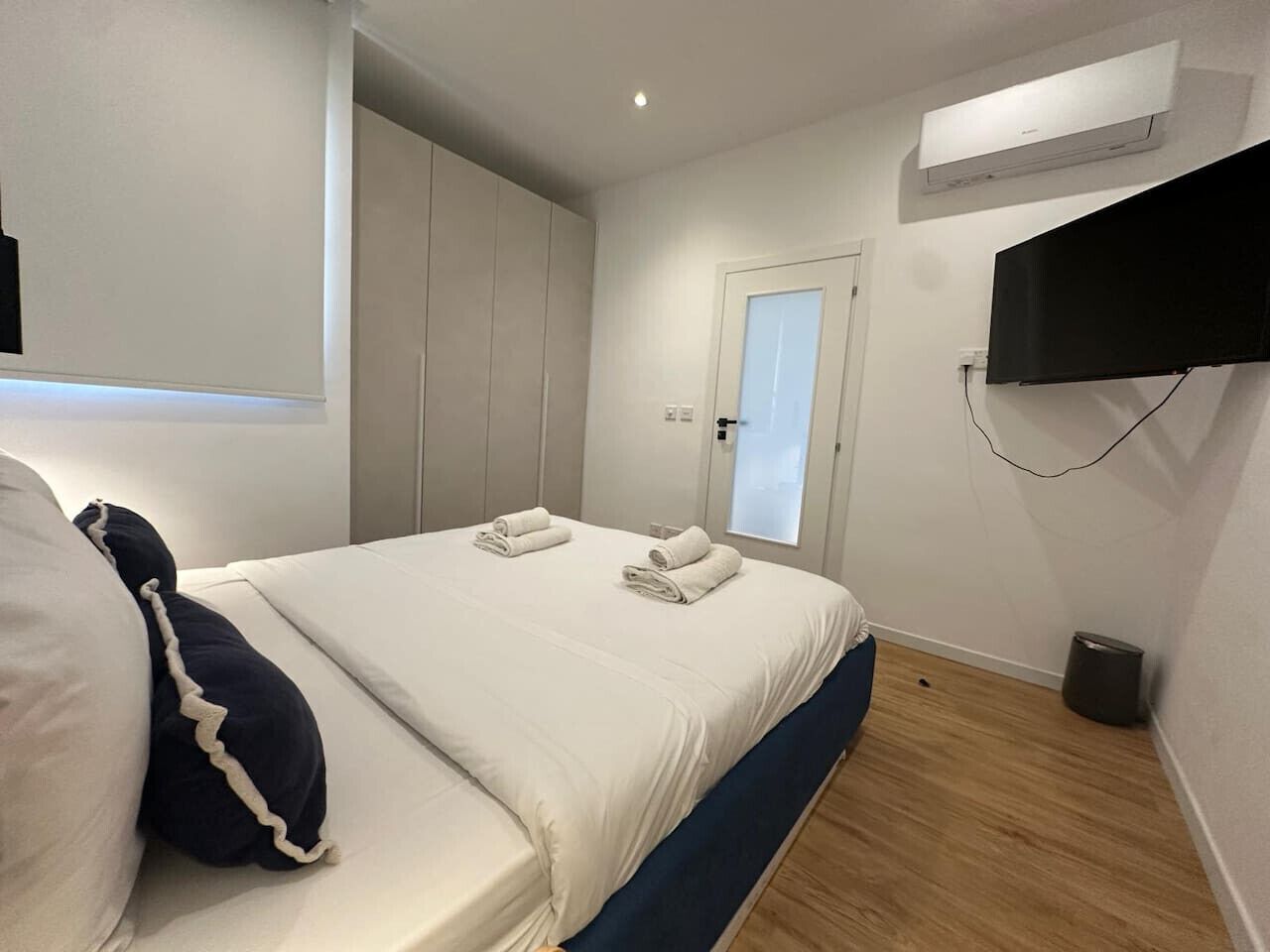 Ein Schlafzimmer mit einem Bett, einem an der Wand montierten Fernseher und einer Klimaanlage.