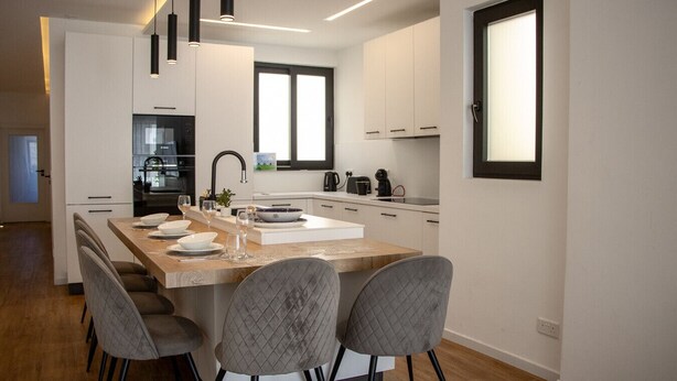 Una cocina moderna con una isla central, electrodomésticos integrados e iluminación colgante.