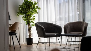 Una sala de estar moderna con dos sillones oscuros, una mesita redonda y una planta en maceta.