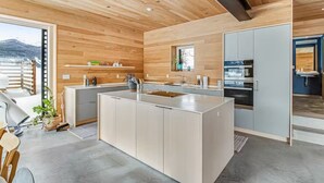 Een moderne keuken met een centraal eiland, houten plafond en inbouwapparatuur.