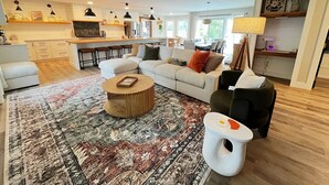 Ein modernes Wohnzimmer mit einer Eckcouch, einem Couchtisch und einem Essbereich im Hintergrund.