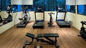 Ein Fitnessraum mit Laufbändern, Crosstrainern und Kurzhanteln.