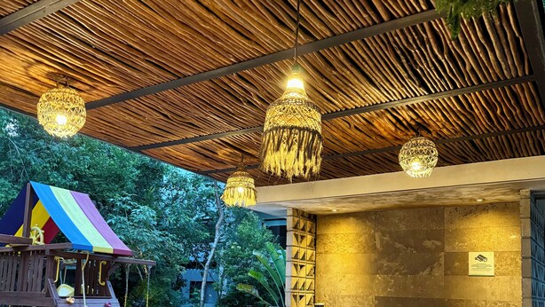 Eine Terrasse im Freien mit einem Holztisch und -stühlen, einer Kinderspielanlage und einem Grillplatz.