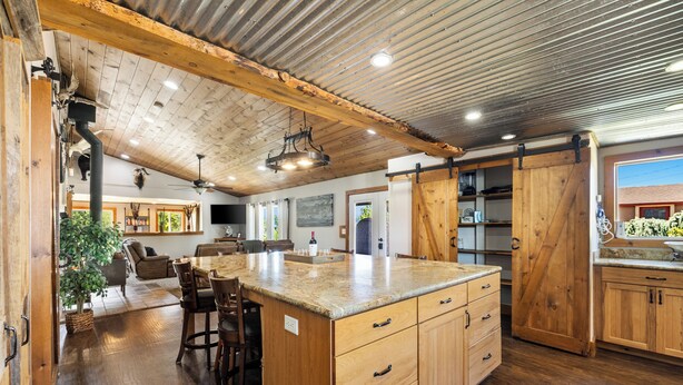 A spacious kitchen with wooden cabinets, a large island, and a dining area with chairs.