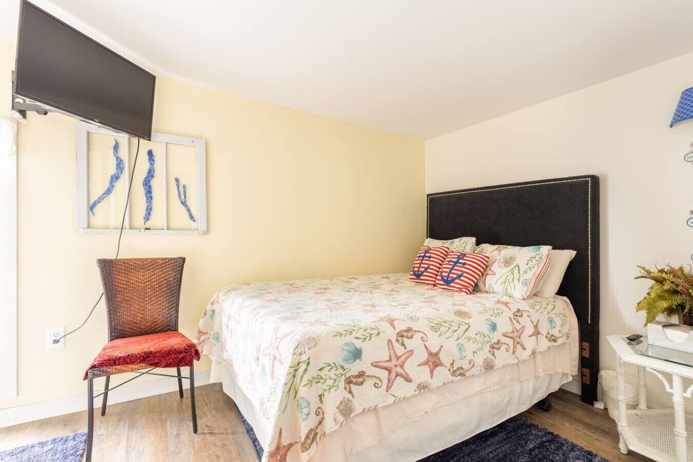 A bedroom with a bed, a chair, a desk, and wall art.