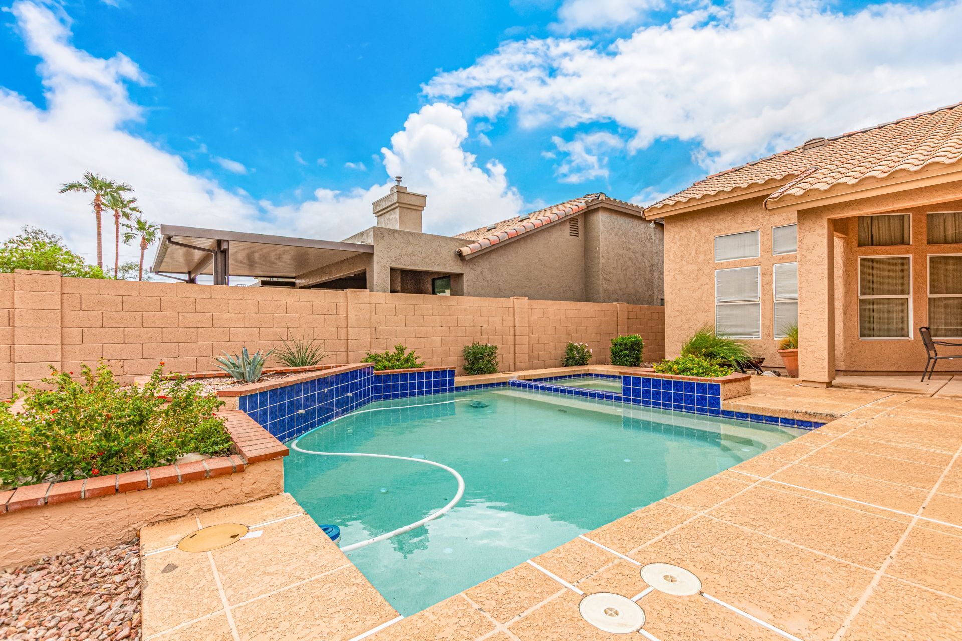 Ein Garten mit Swimmingpool, einer Ziegelmauer und einer Terrasse.