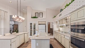 A spacious kitchen with modern appliances, a central island, and a dining area with a chandelier.
