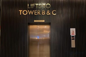 An elevator with a sign reading 'LIFTS TO TOWER B & C' and a control panel with a digital display. - Inap II, Suterabay by Ayuhouz (Kota Kinabalu)