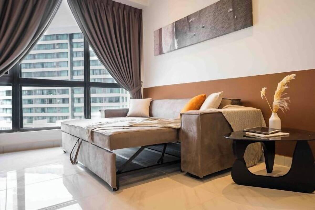 A modern bedroom with a bed, a side table, and a view of a cityscape through large windows.