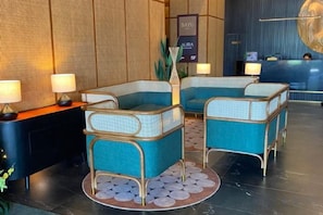 A reception area with two blue cushioned chairs, a reception desk, and a wall-mounted sign. - Inap II, Suterabay by Ayuhouz (Kota Kinabalu)