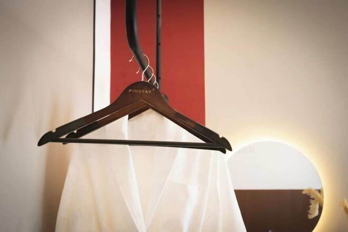 Un cintre portant l’étiquette « PINSTAY+ », avec un vêtement blanc suspendu en dessous.