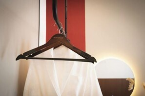 Un cintre portant l’étiquette « PINSTAY+ », avec un vêtement blanc suspendu en dessous.