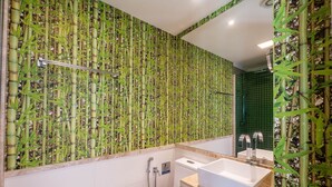Une salle de bain avec un papier peint à motifs de bambou, une douche et deux lavabos.