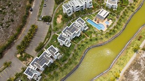 Vue aérienne d’un complexe résidentiel moderne comprenant plusieurs bâtiments, une piscine et une rivière.