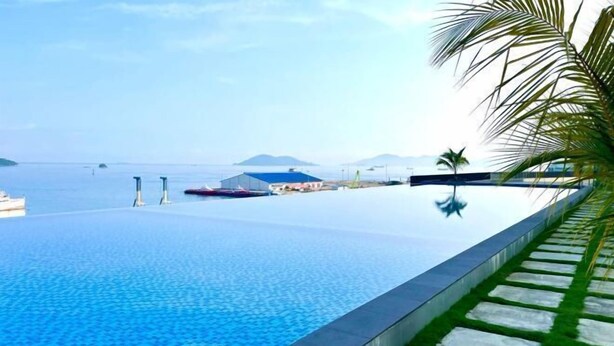 A infinity pool with a clear view of the sea and distant mountains.