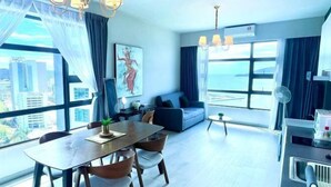 A modern living room with a dining area, large windows with a city view, a sofa, and a small table.