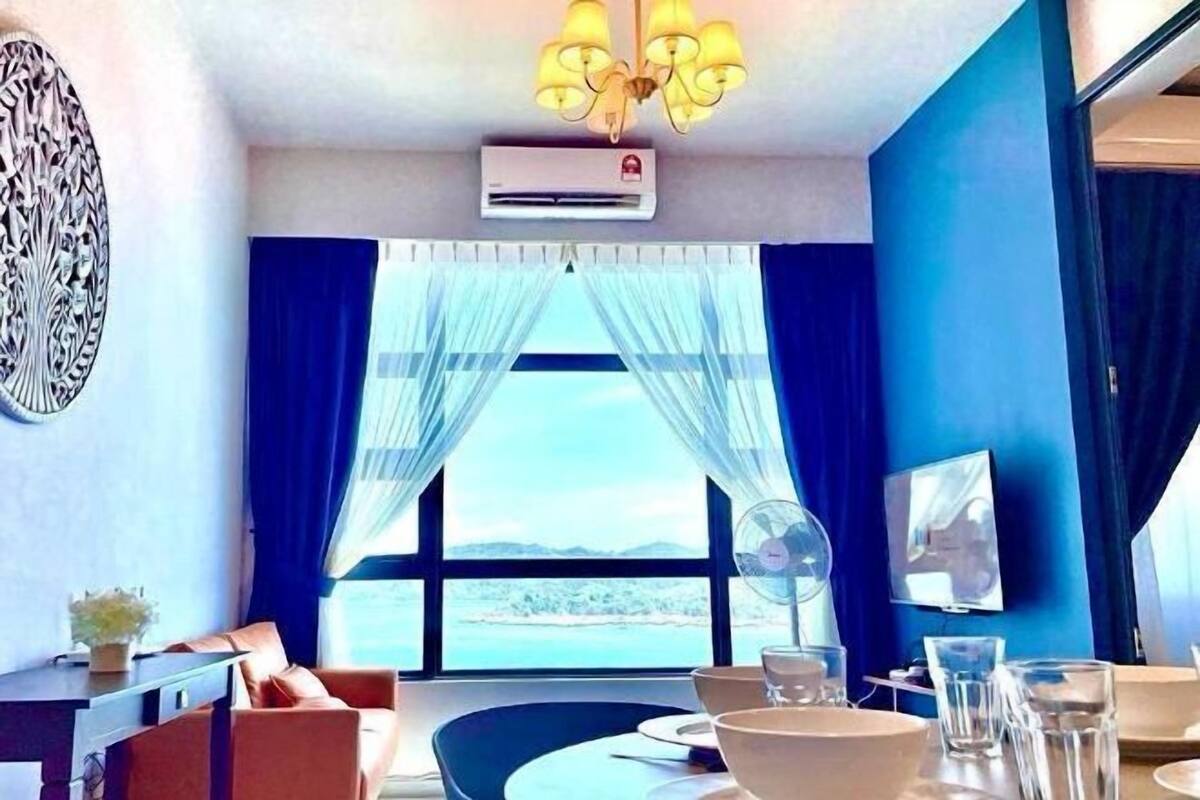 Habitación de hotel con un ventanal grande, una araña, aire acondicionado, televisor de pantalla plana y una zona de comedor con mesa y sillas.