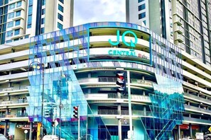 A multi-story building with a glass facade and the sign 'JQ Central 85th Street'. - Jesselton Quay - Sunset Ocean View Apartments by Quality Home Living (Kota Kinabalu)