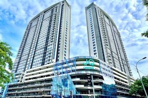 A high-rise building with multiple floors, a central atrium, and a prominent signage. - Jesselton Quay - Sunset Ocean View Apartments by Quality Home Living (Kota Kinabalu)