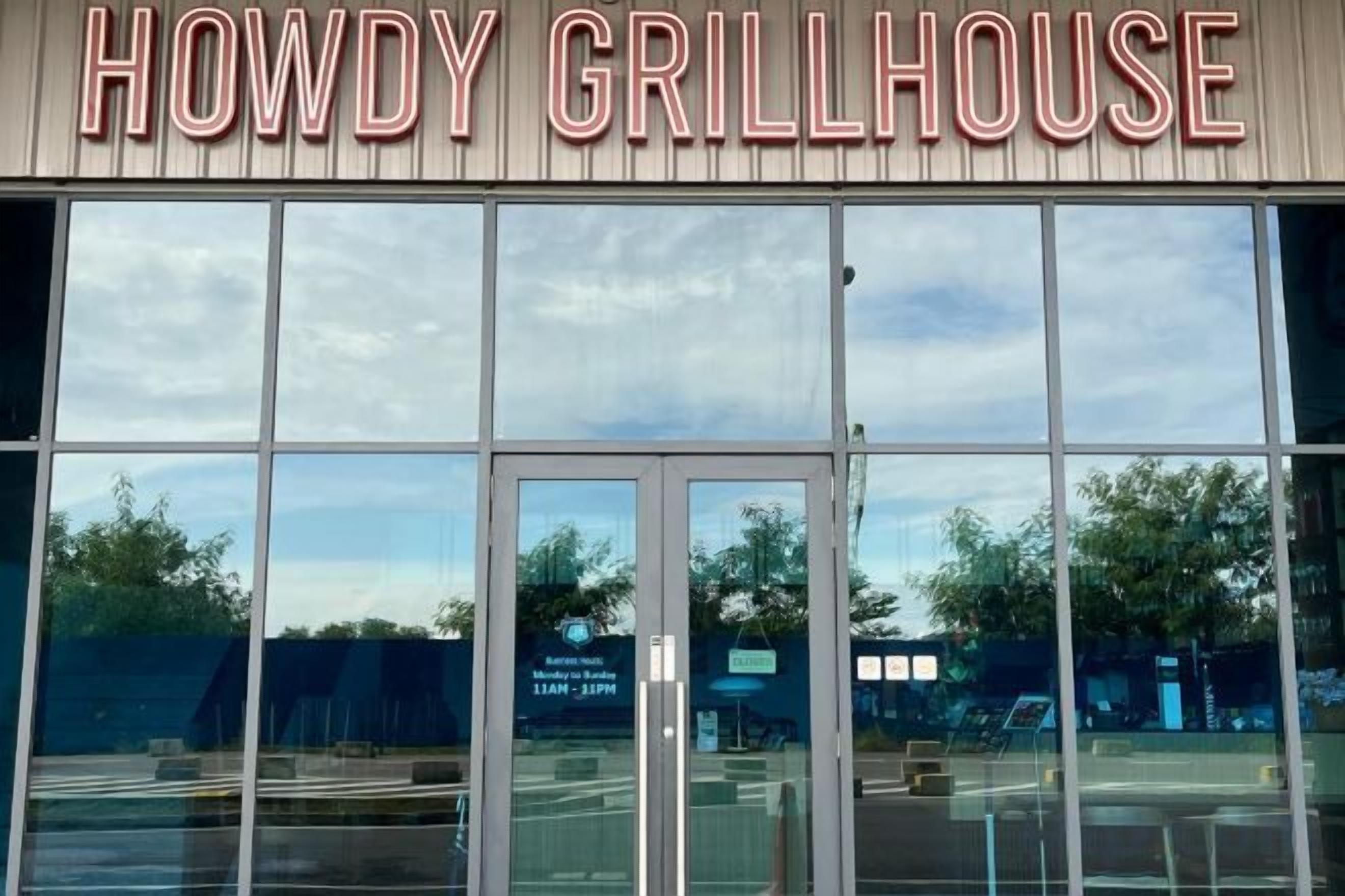 Vue dégagée de l’extérieur du Howdy Grillhouse, montrant l’entrée et le parking.
