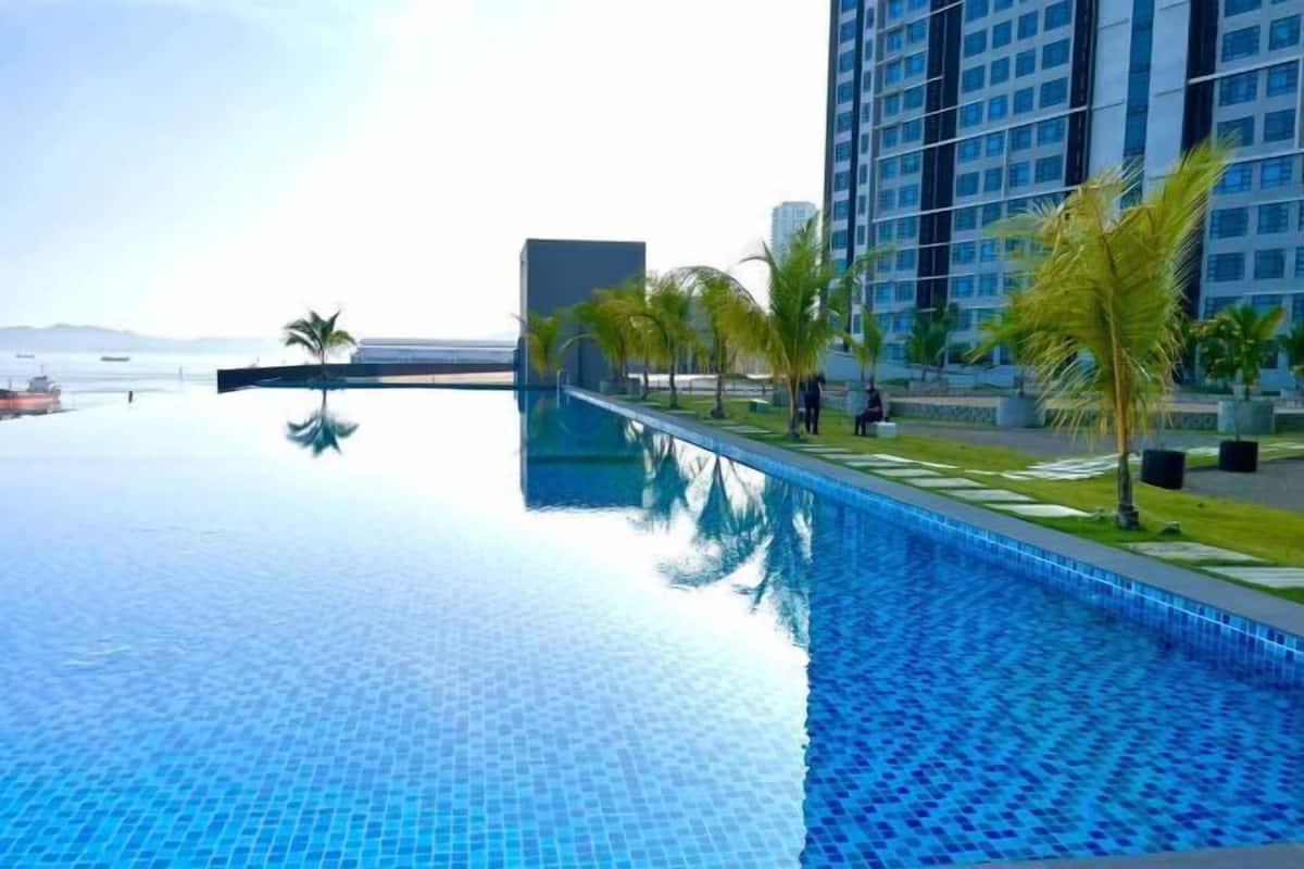 Una piscina con vista despejada al mar y un edificio alto al fondo.