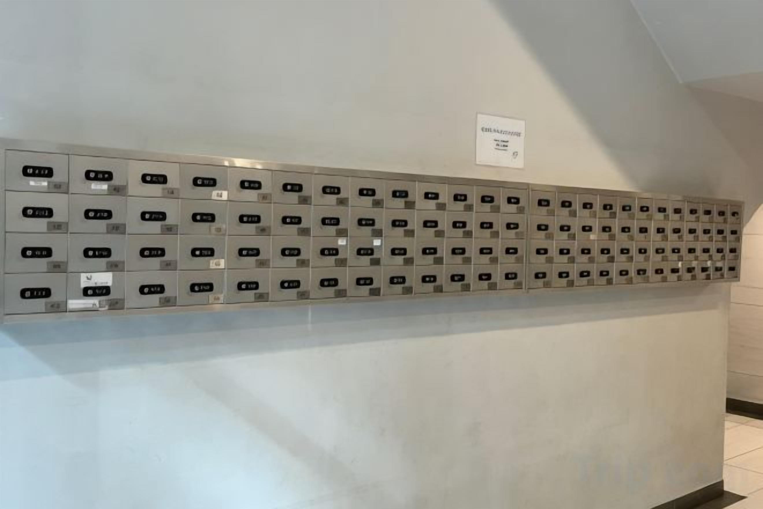 Uma fileira de armários metálicos com números, fixados numa parede.