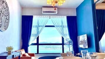 A room with a dining table, chairs, a chandelier, an air conditioning unit, and a large window with curtains.