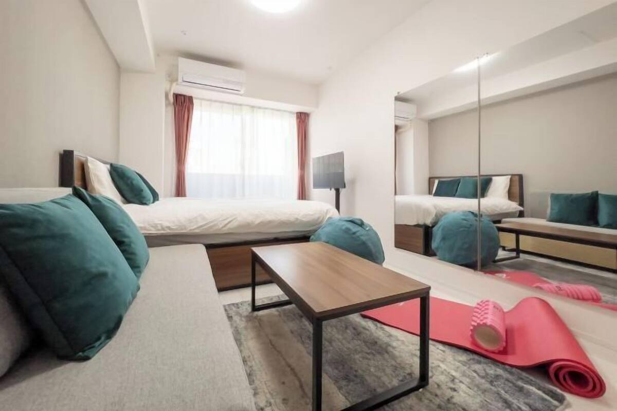 Une chambre d’hôtel moderne équipée d’un lit, d’un canapé, d’une petite table, d’un miroir et de tapis de sol pour faire de l’exercice.