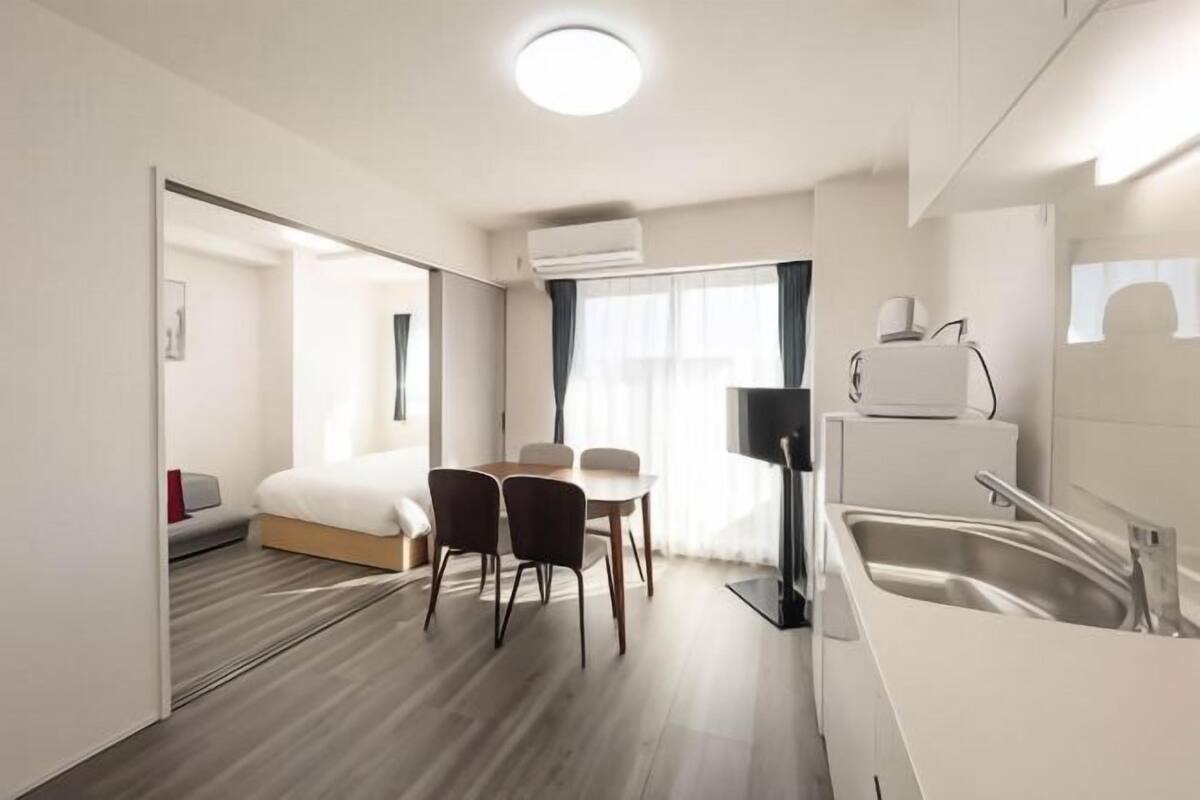 Une chambre d’hôtel moderne comprenant un lit, un petit coin repas, une kitchenette et une salle de bain.