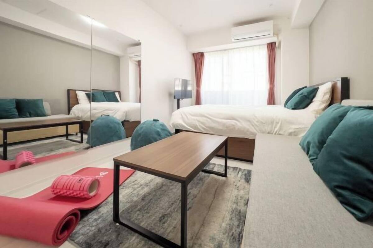 Une chambre d’hôtel moderne équipée de deux lits, d’une petite table, d’un tapis de yoga et d’une télévision.