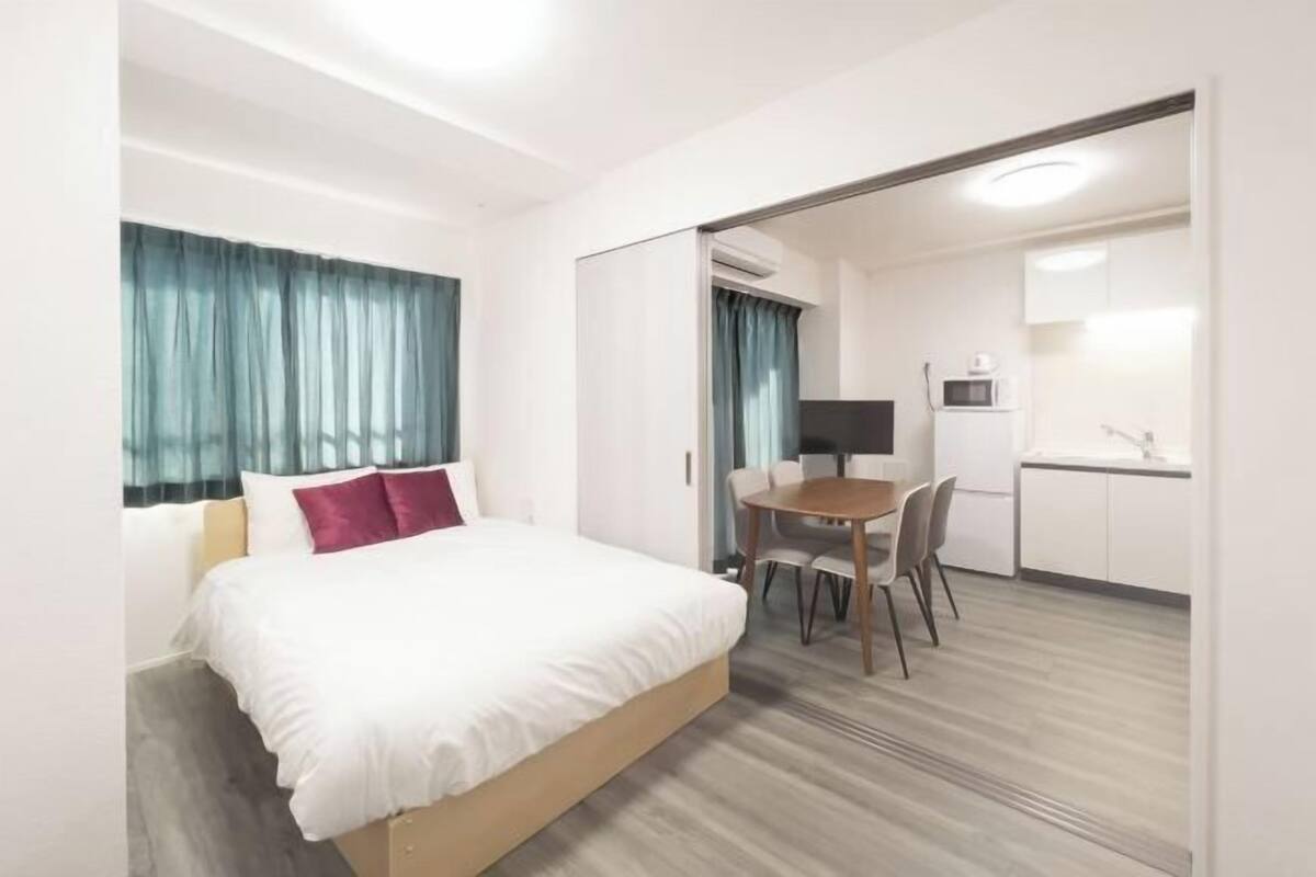 Une chambre d’hôtel équipée d’un lit, d’un bureau, d’une chaise, d’un four à micro-ondes et d’une petite kitchenette.
