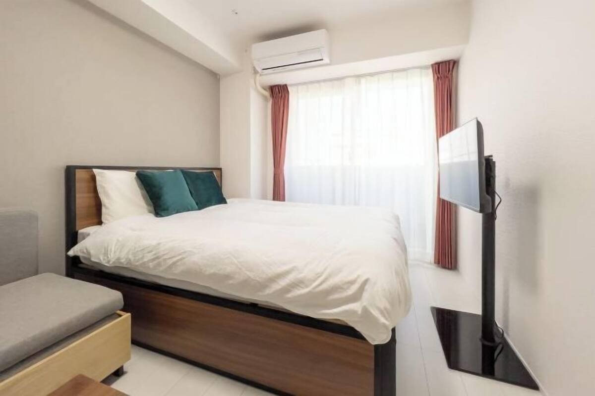Une chambre d’hôtel moderne équipée d’un lit, d’une télévision et d’un système de climatisation.