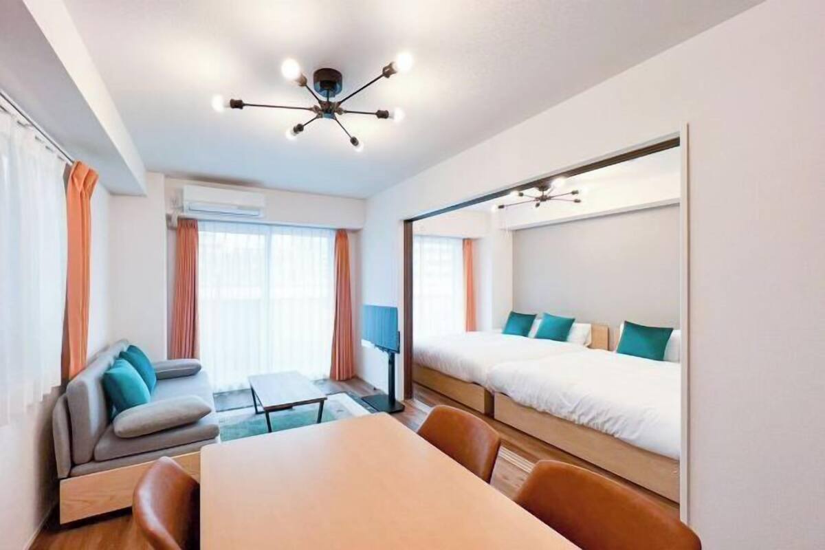 Une chambre d’hôtel moderne avec un canapé, un lit avec une tête de lit, une table à manger et un luminaire au plafond.