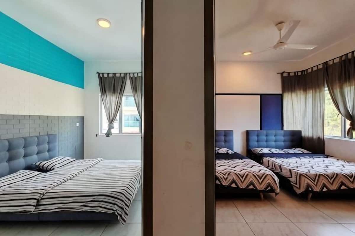 A hotel room with a large bed, two smaller beds, a ceiling fan, and a window with curtains.