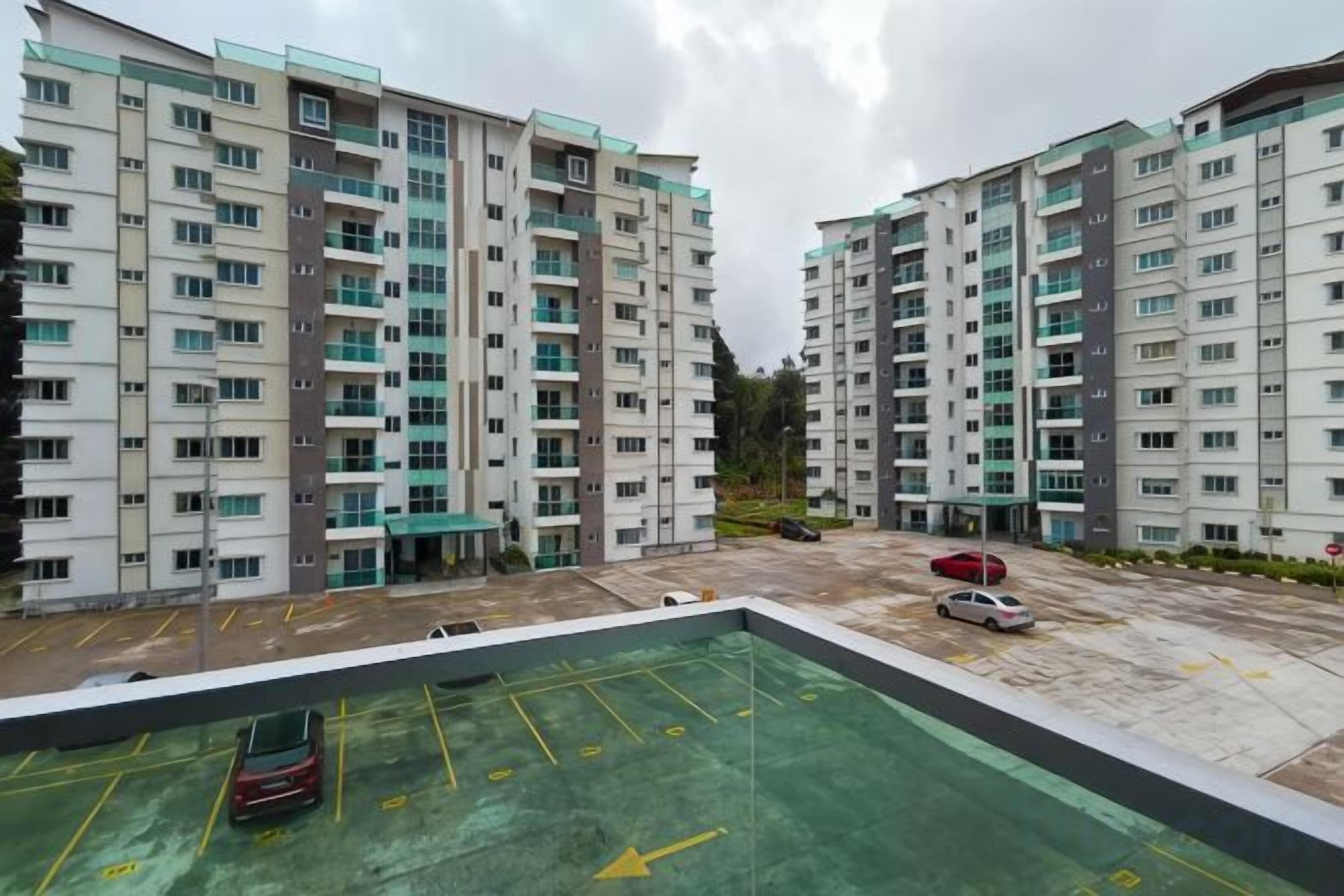 A multi-story residential building with a parking area in the foreground.