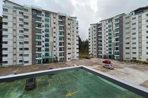 Un immeuble résidentiel à plusieurs étages, avec un espace de stationnement situé à l’avant.