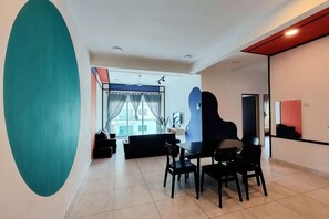 A modern living room with a dining area, large windows, and a view of the street.