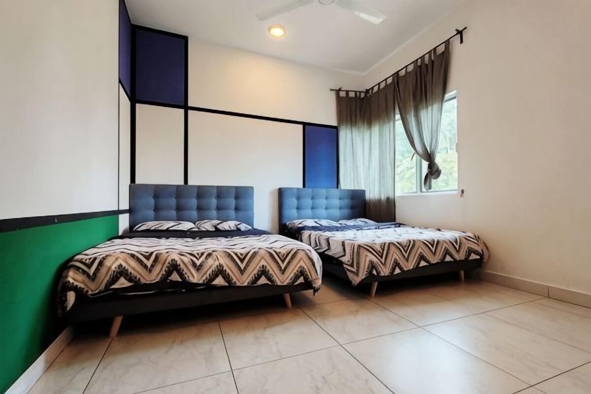 A room with two beds, a ceiling fan, a window with curtains, and a green accent wall.