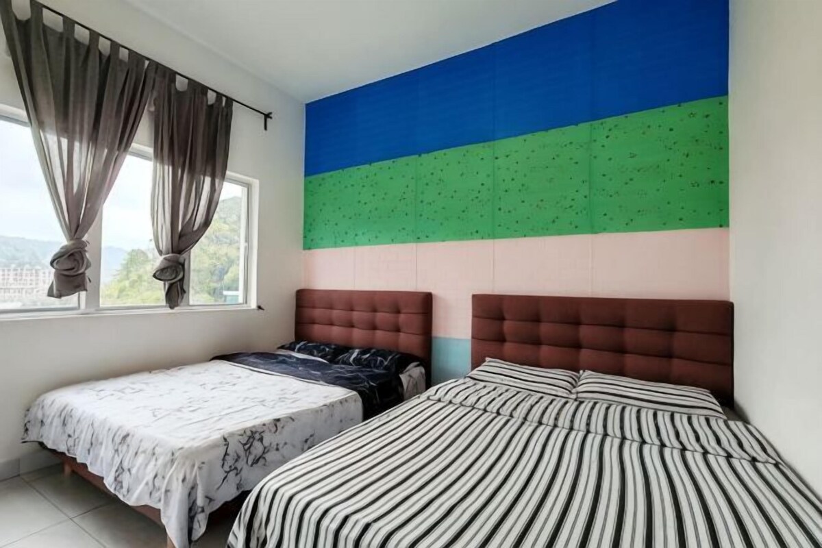 A bedroom with two beds, a large window with curtains, and a colorful wall.