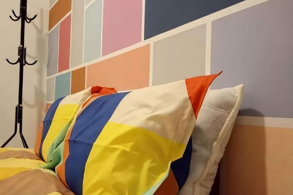 A bed with colorful pillows and a striped wall.