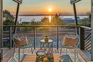 A balcony with two chairs, a small table, and a tray with candles and a pitcher.