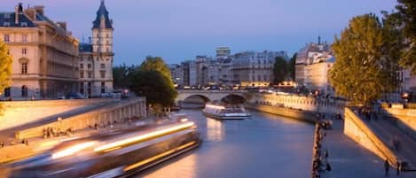 Un río con un puente, edificios y un tren en movimiento.