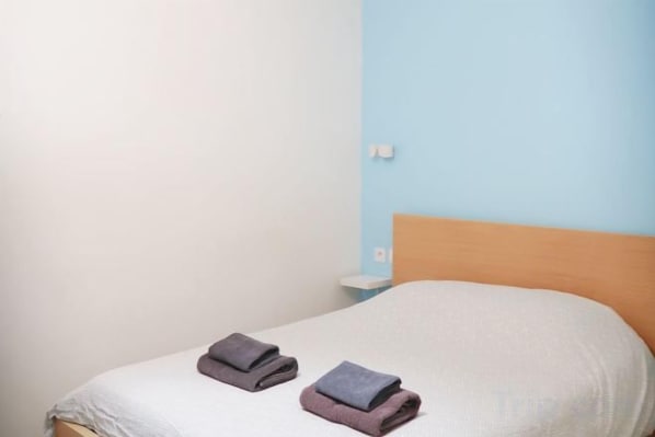 A single bed with a white mattress and a wooden headboard. There are two folded towels on the bed. - Chic & Modern Studio in Centre Paris Rambuteau (Paris)