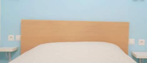 A bed with a wooden headboard, white bedding, and two towels on either side.