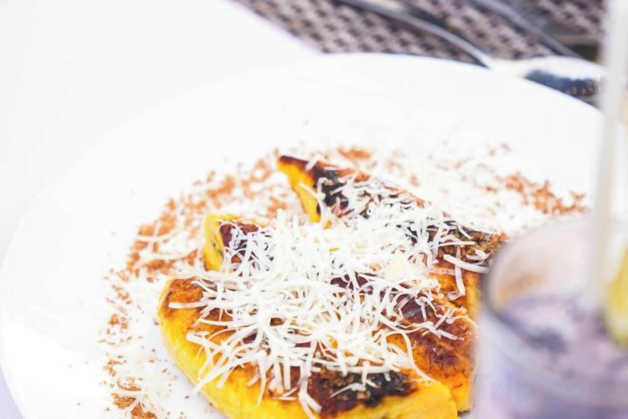 Une assiette contenant un plat recouvert de fromage râpé.