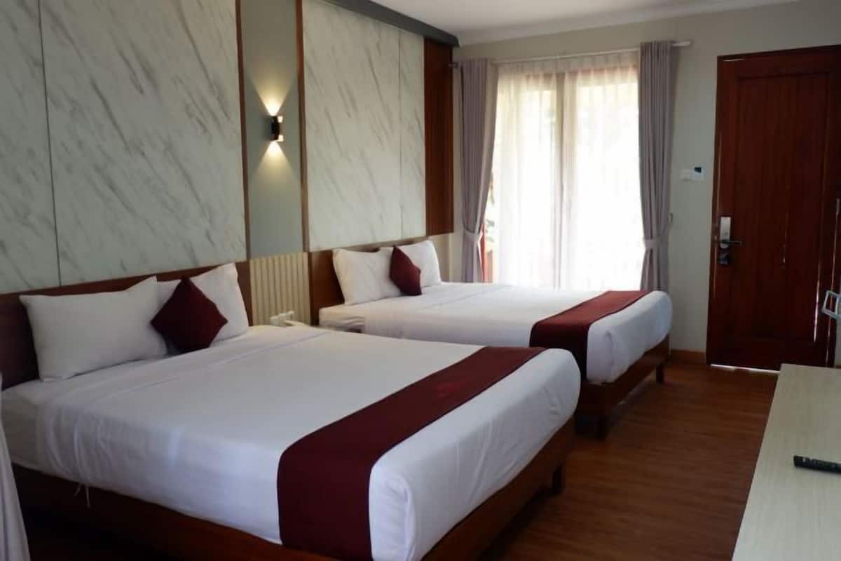 Una camera d'albergo con due letti, pavimento in legno, parete in marmo e una finestra con tende.
