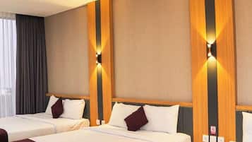 A hotel room with three beds, a wooden accent wall, and a window with curtains.