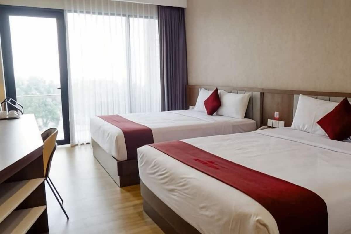 Una camera d'albergo con due letti, una scrivania e una sedia.